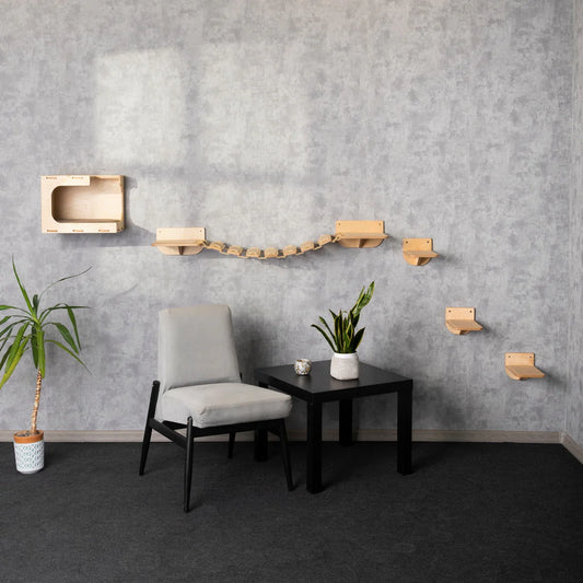 Cosy Cat House with Steps & Built-in Cat Bridge: Stylish wooden cat furniture set against gray wall, featuring cubby, bridge, and steps. Modern living room decor with chair, table, and plants.
